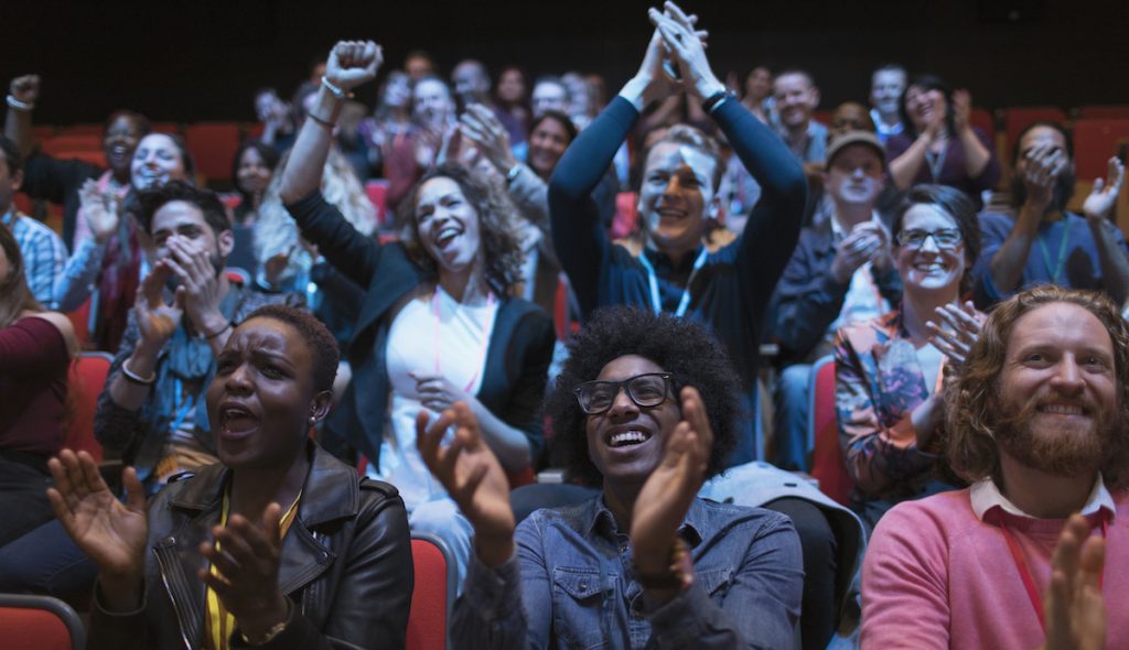 Excited audience clapping in dark room