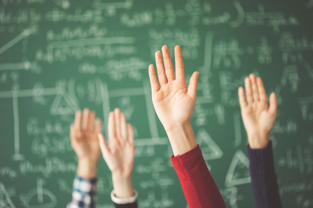 Students with their hands raised in the classroom